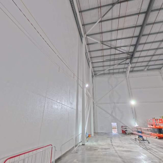 Concrete panel walls coated in Airtight White and left on show as the finished white surface, in a tall naturally lit space