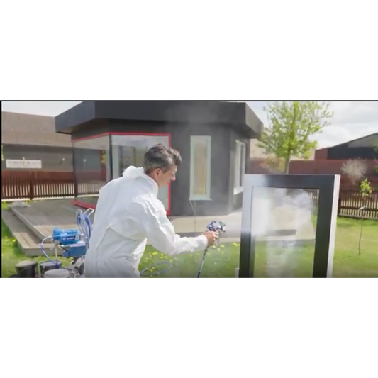 Installer spray-applying Intelligent Protect liquid window protection film to glazing on a construction site