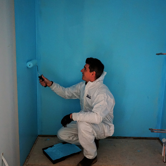 Installer roll-applying Poseidon waterproofing membrane to bathroom wall before tiling