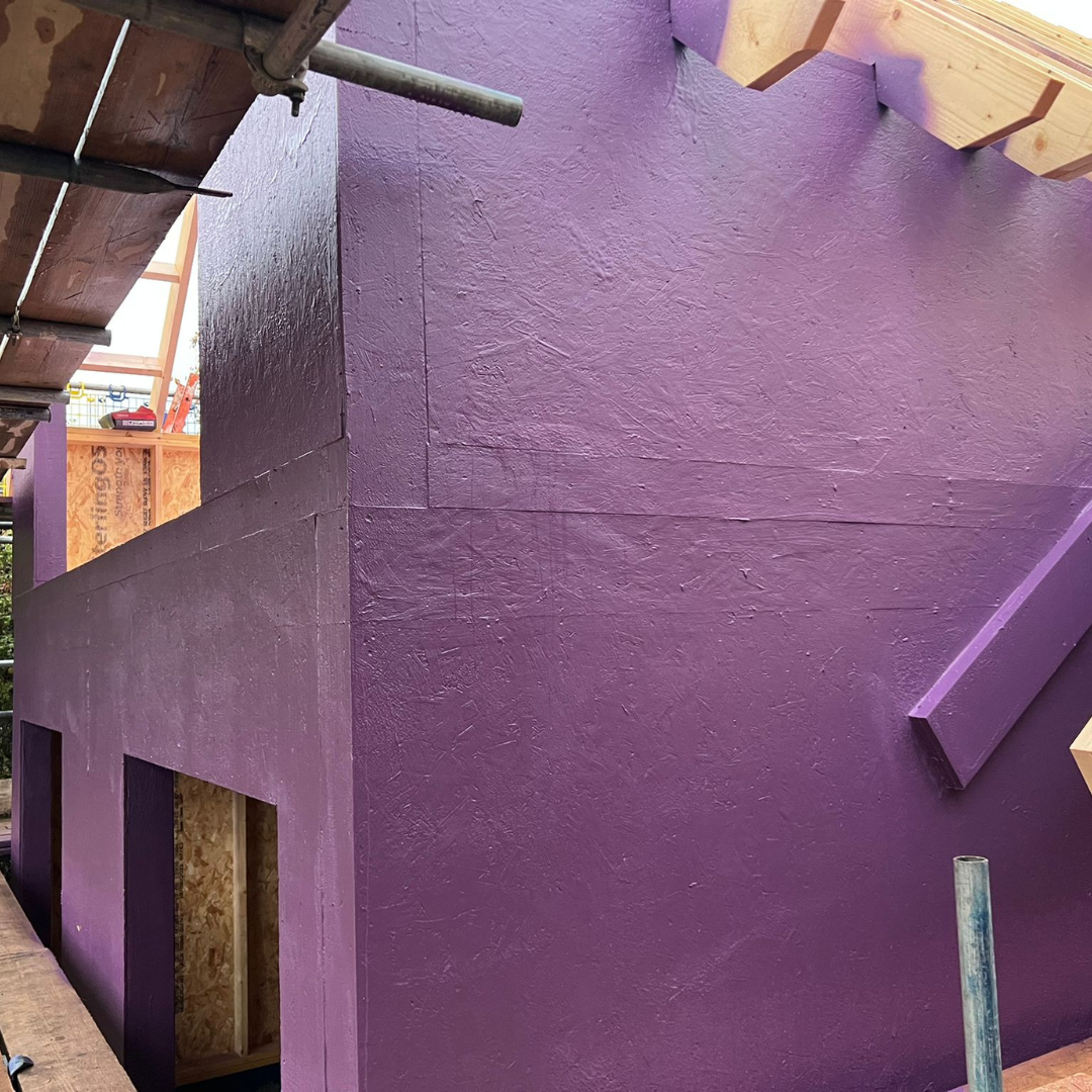 Exterior building façade coated with Passive Purple External liquid waterproofing and fire-rated membrane during construction
