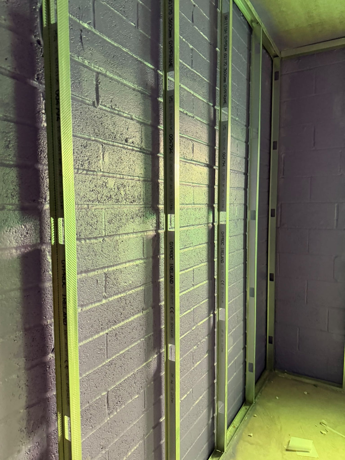 Blockwork inner leaf coated with Passive Purple liquid airtight membrane, with metal stud lining framework fixed in front of it