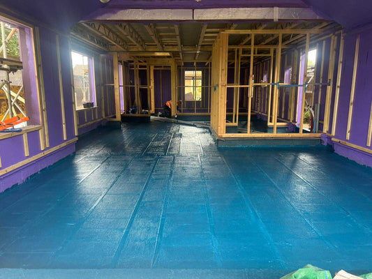 Close-up of liquid damp proof membrane being applied with a roller to a concrete floor, forming a seamless barrier